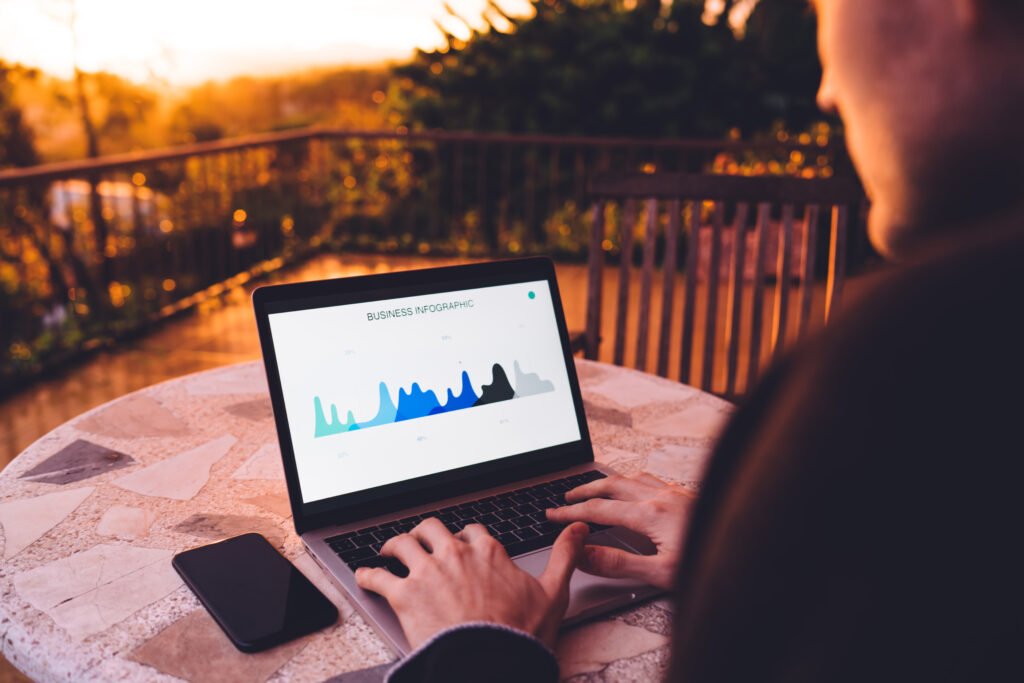Cropped image of skilled marketer working remotely with analytic revenue and web infographics displayed on laptop screen, business man using wireless internet connection for analyzing diagram