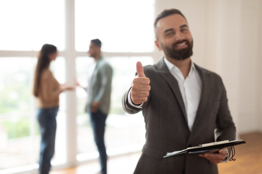 Real Estate Business, Sale and People Concept. Portrait of happy smiling realtor or businessman with clipboard showing thumbs up gesture, selective focus. Customers rejoice purchase