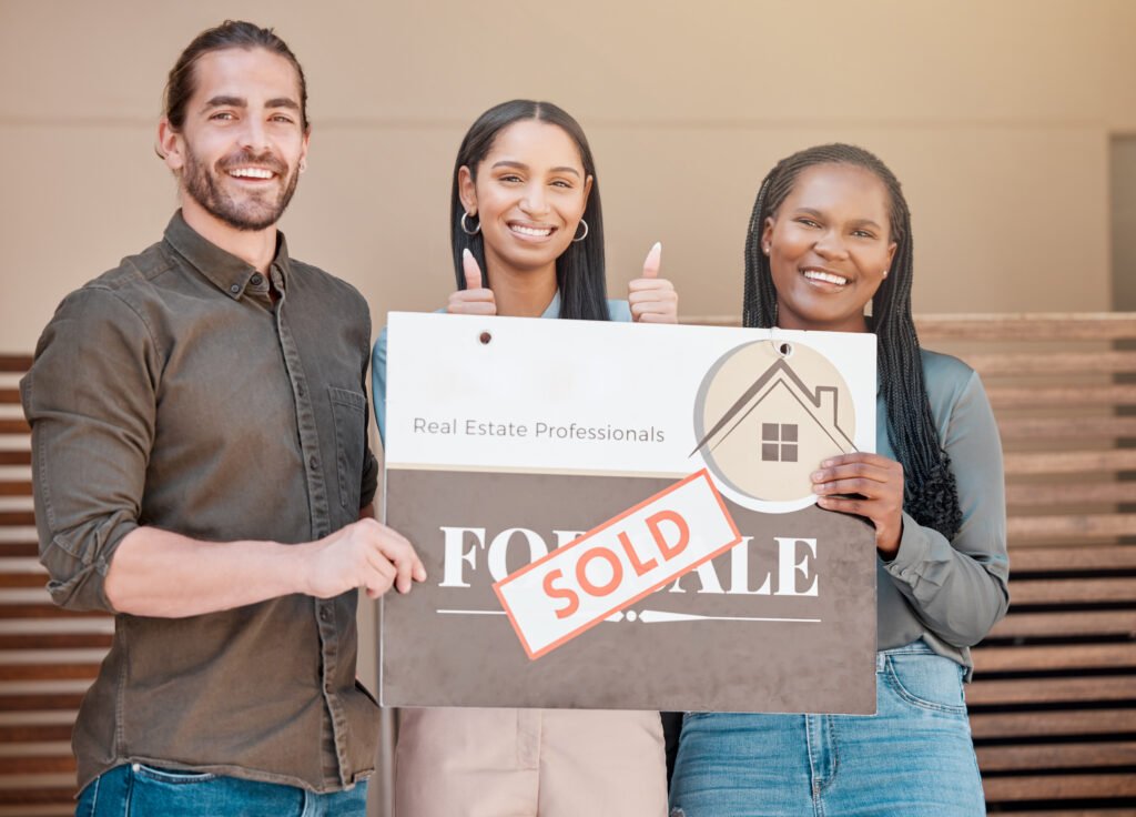 Shot of a young couple and their real estate agent holding up a sold board outside their house.