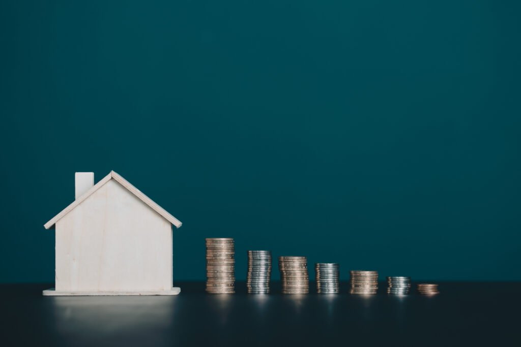 Coin stack with house model on table with copy space. Realtor, mortgage, your house, home loan concept.