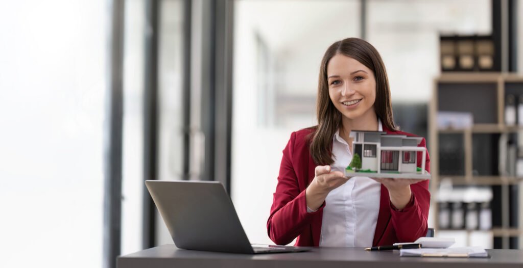 Woman holding white house model in hand. Realtor approval home loan and real estate concept.